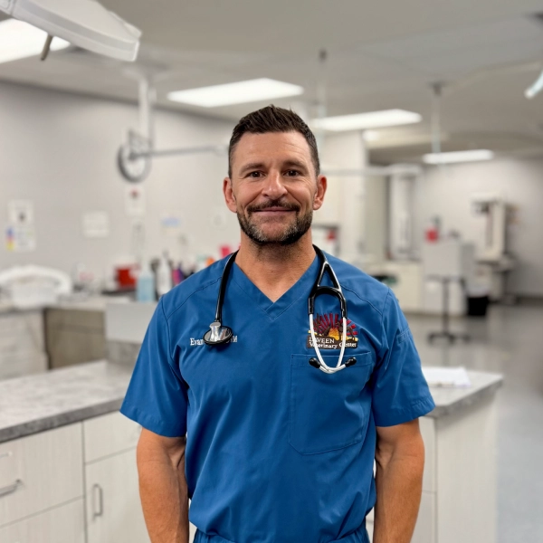 A man wearing blue scrubs and a stethoscope stands in a medical setting.