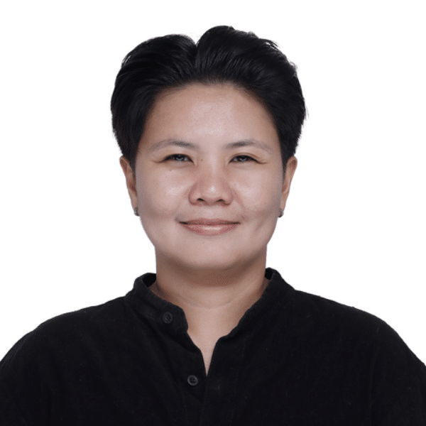 Janz A person in black scrubs smiles while standing behind a counter with small decorative items and business cards.